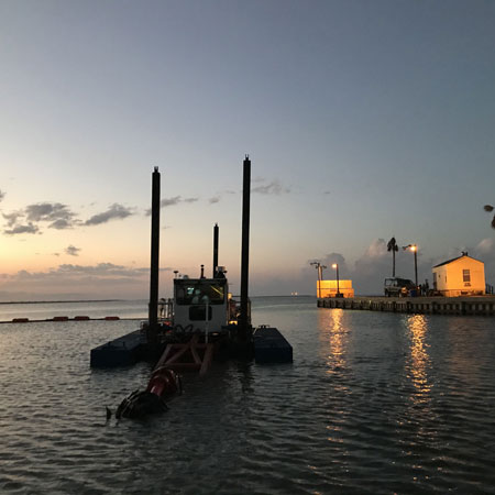 dredging boat in water at sunset